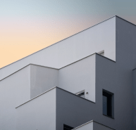 RCM Construção - Fachada de um edifício moderno com ângulos e linhas geométricas em tons de cinza e branco.