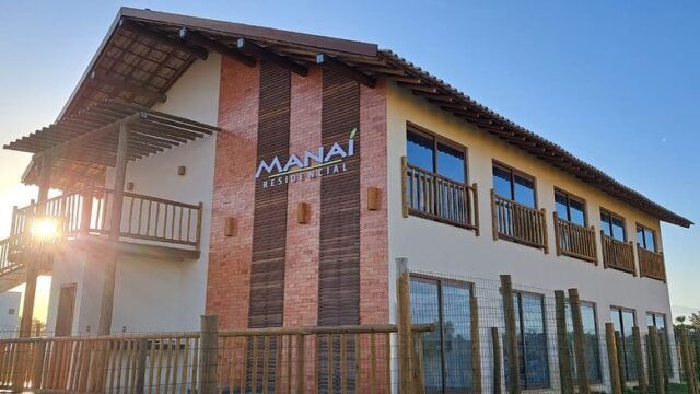 RCM Construção - Fachada do Manai Residencial com janelas grandes e estrutura de madeira.